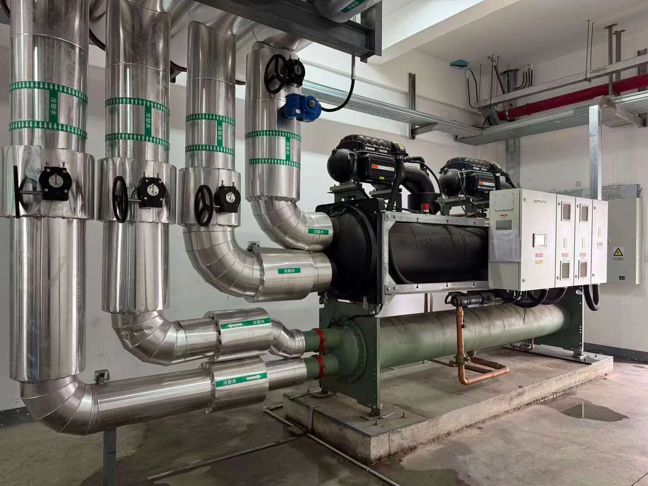Water-cooled chiller in a plantroom with AUCHIEVE lettering visible on its cabinet